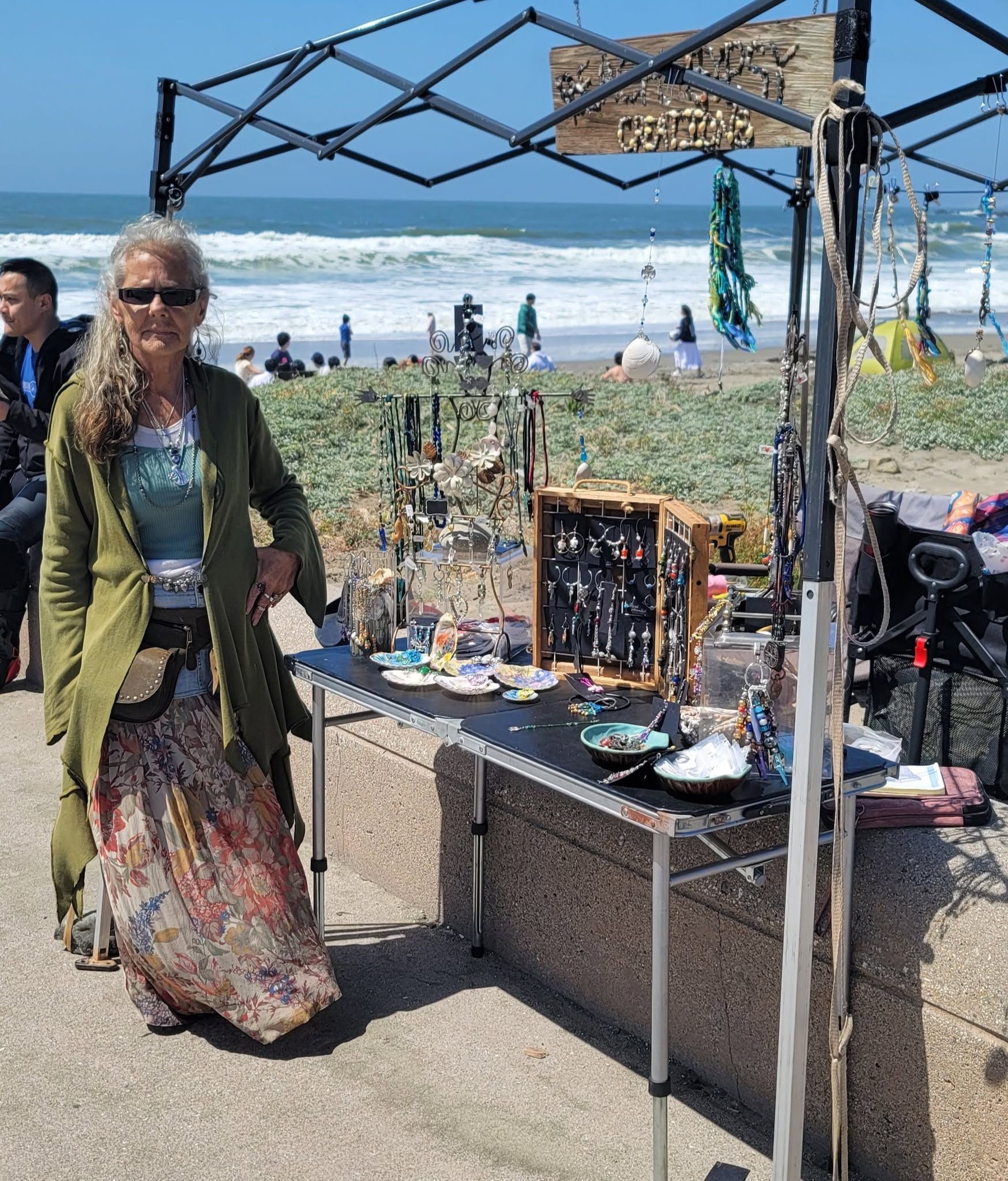 Dana Fink at her Beach Gypsy Creations stall on the sand, ocean behind the tent