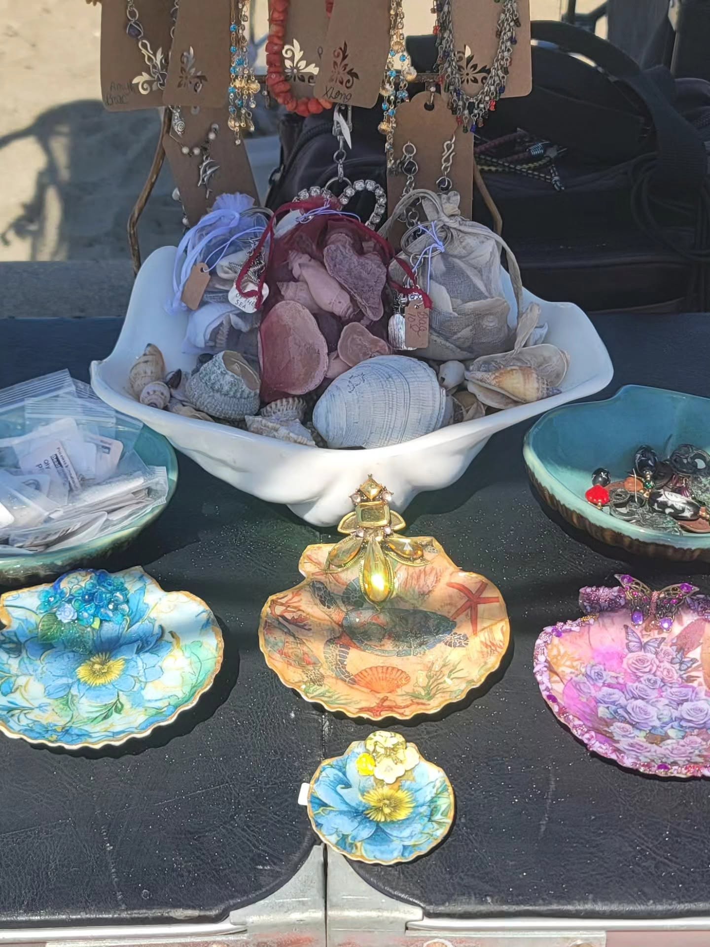 Close table: blue floral scallop, turtle shell with gold bee, purple butterfly, jewelry